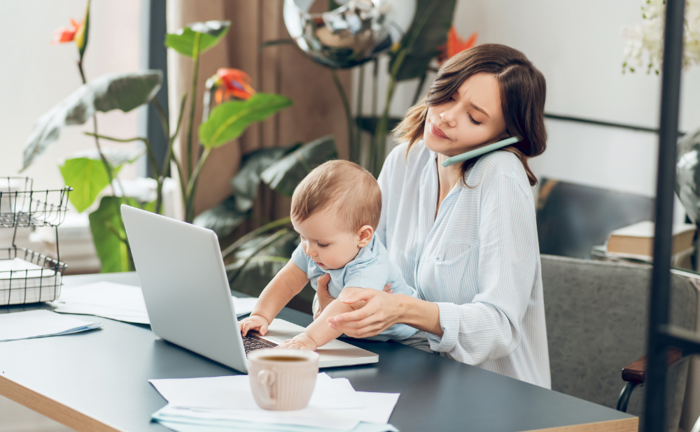 Busy self employed mom running her business at a laptop with baby.